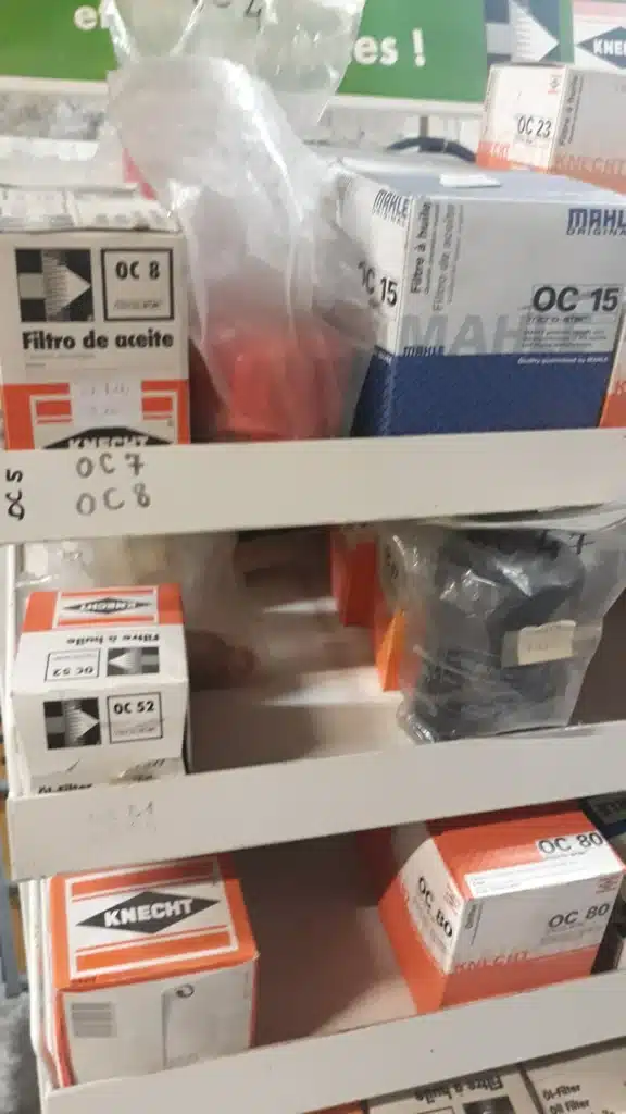 Étagères d'un magasin de pièces auto avec boîtes de filtres à huile Knecht et Mahle. Réf. OC 8, OC 15, OC 23, OC 52, OC 80 visibles.