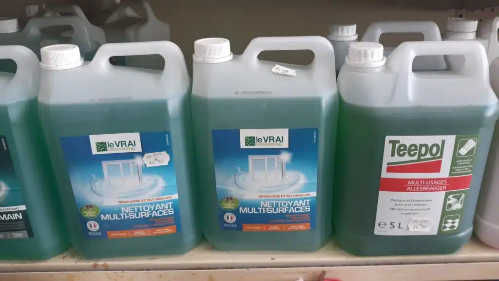 Bidons de nettoyants professionnels le VRAI (multi-surfaces, 22,50€) et Teepol (multi-usages 5L, 24,90€) sur étagère. Liquide vert-bleu.