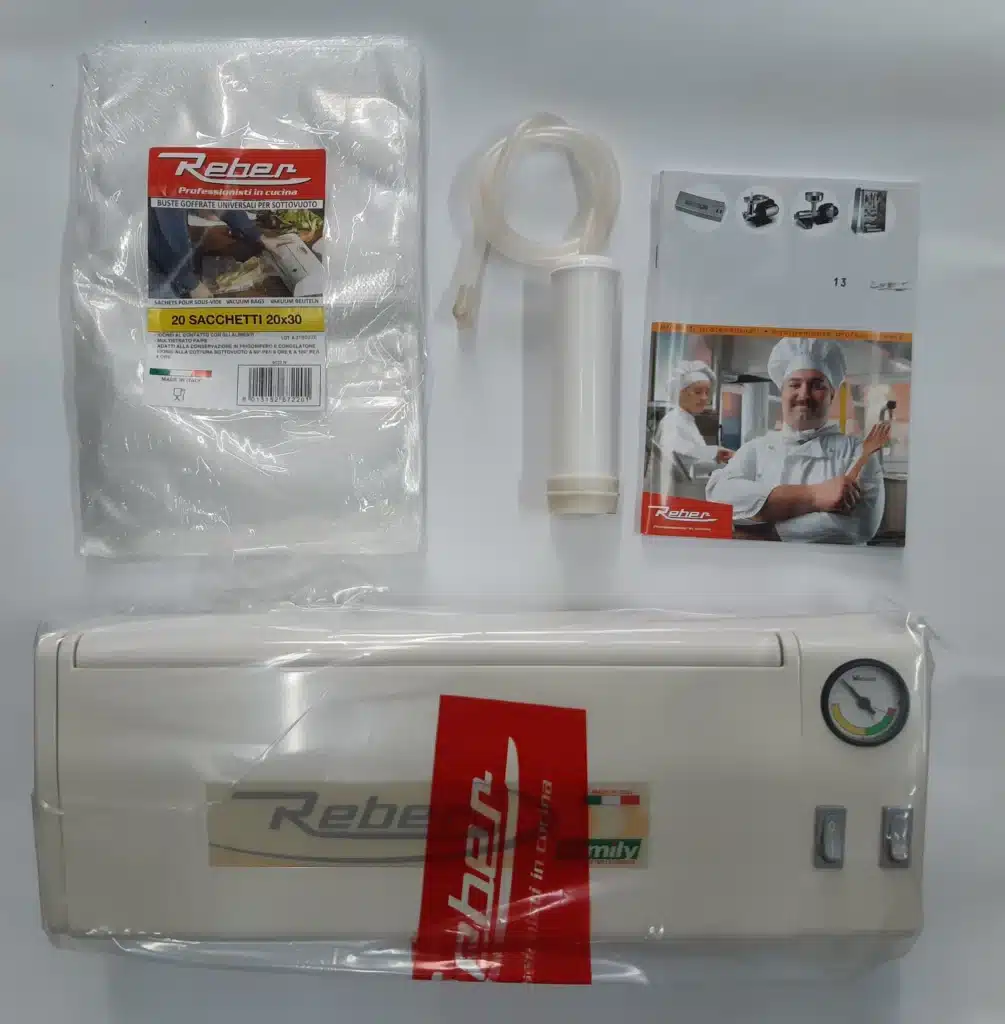 Machine sous vide Reber blanche, avec sacs gaufrés (20x30) et accessoires de pompe. Livrets "Professionisti in cucina" visibles.