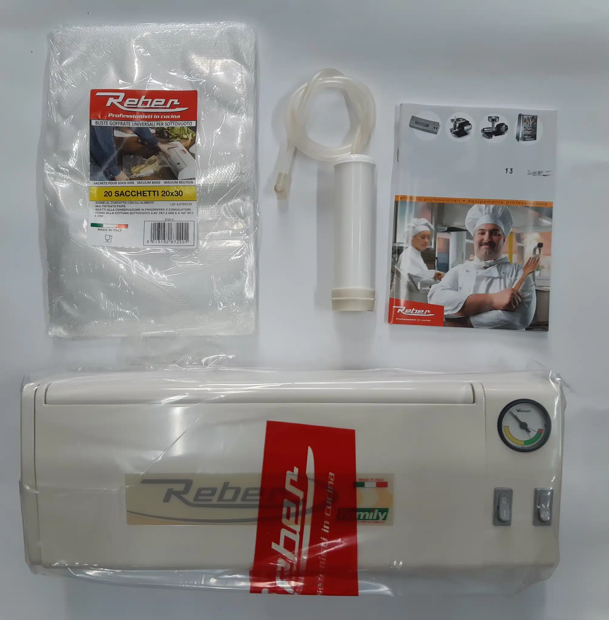 Machine sous vide Reber blanche, avec sacs gaufrés (20x30) et accessoires de pompe. Livrets "Professionisti in cucina" visibles.