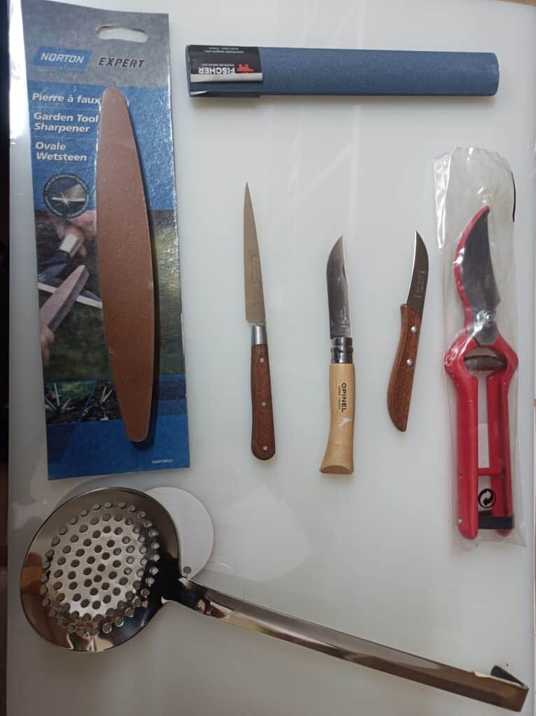 Aiguisage et cuisine: Pierre à aiguiser Norton Expert (Pierre à faux, Ovale Wetsteen), fusil Fischer, 3 couteaux (Opinel), sécateur rouge, écumoire inox.
