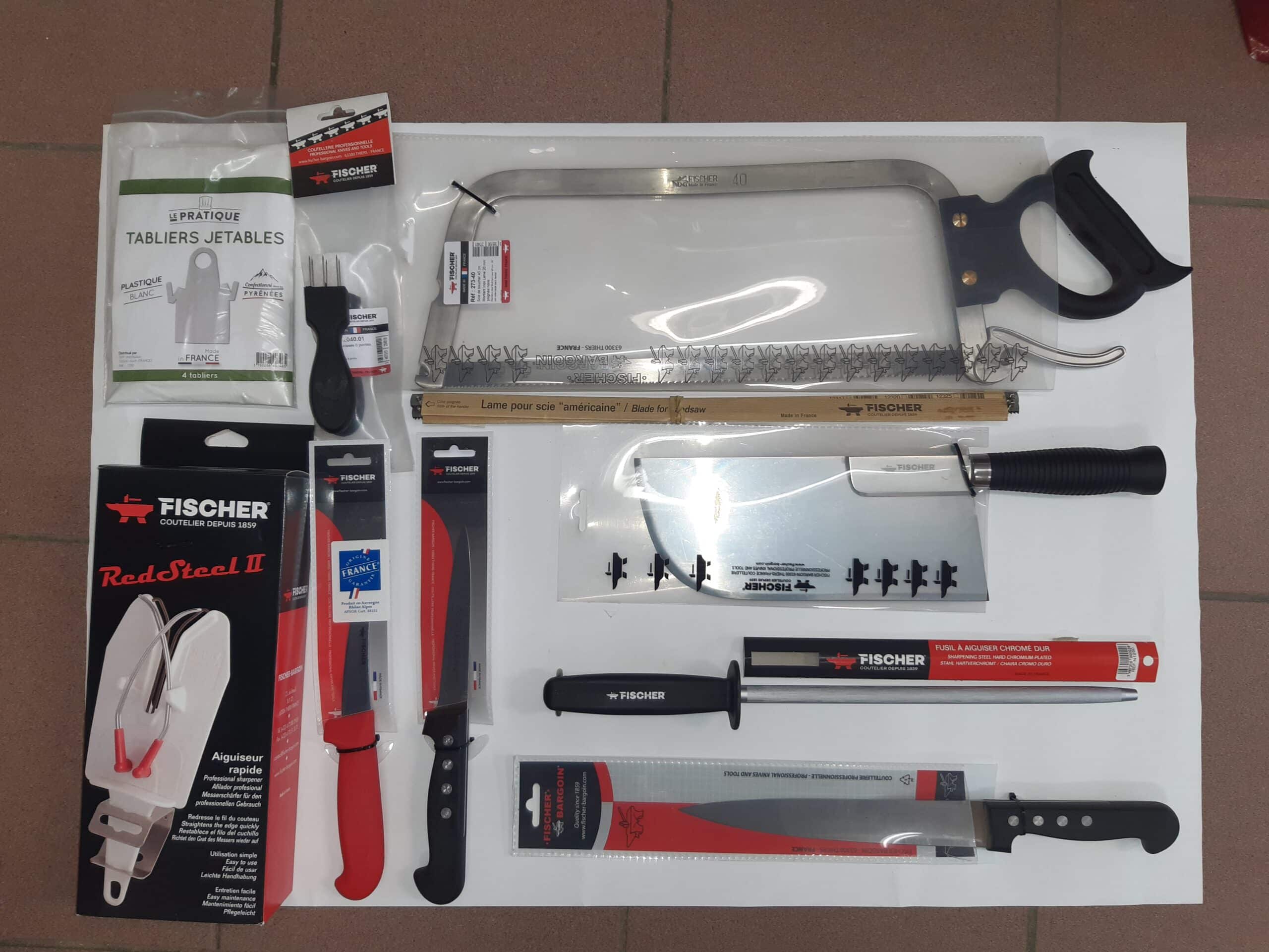 Assortiment d'outils de boucherie et coutellerie Fischer: scie, couteaux pro, fusil à aiguiser, hachoir, aiguiseur RedSteel II, tabliers jetables.